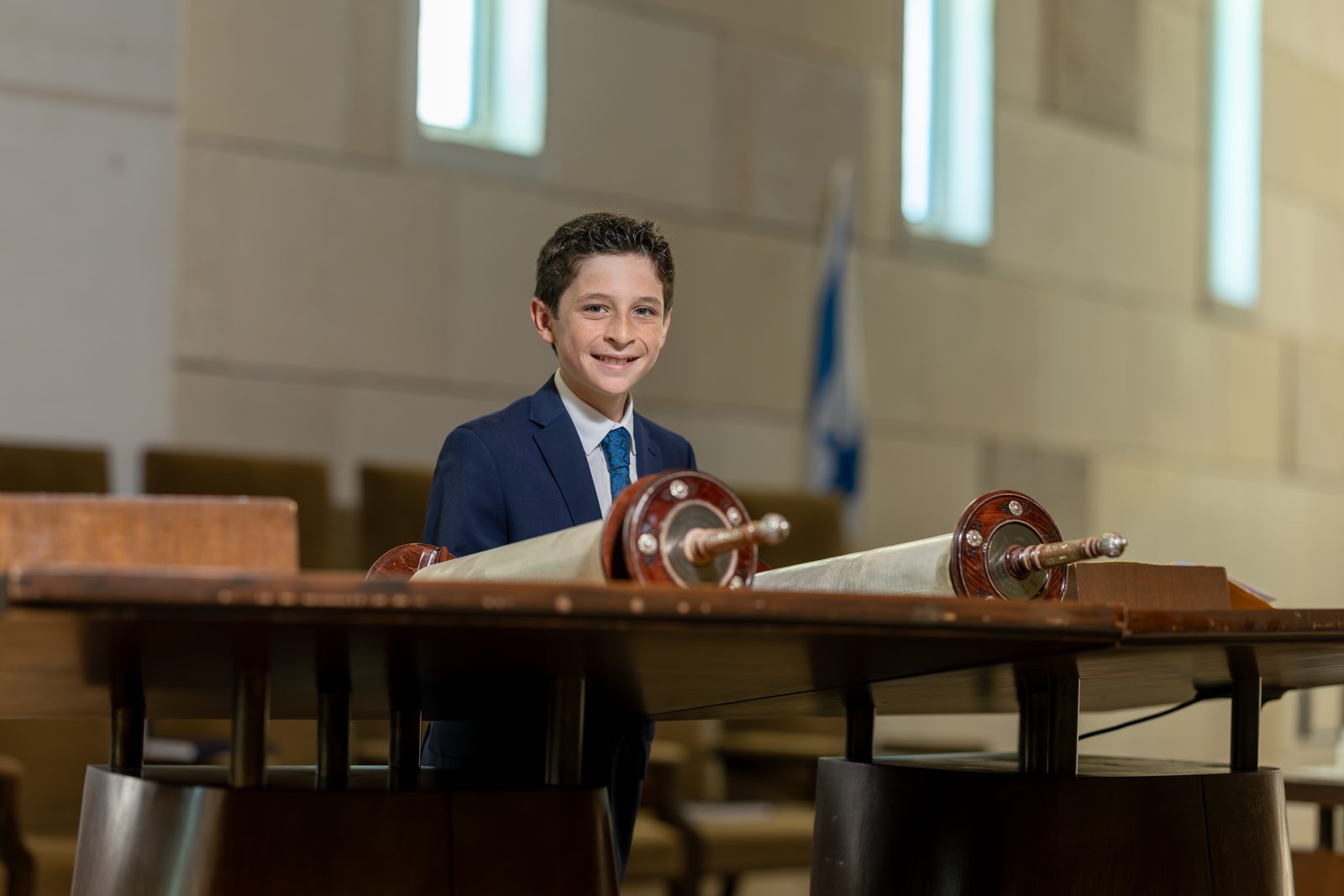 Bar mitzvah boy reading from the Torah scroll at the bimah