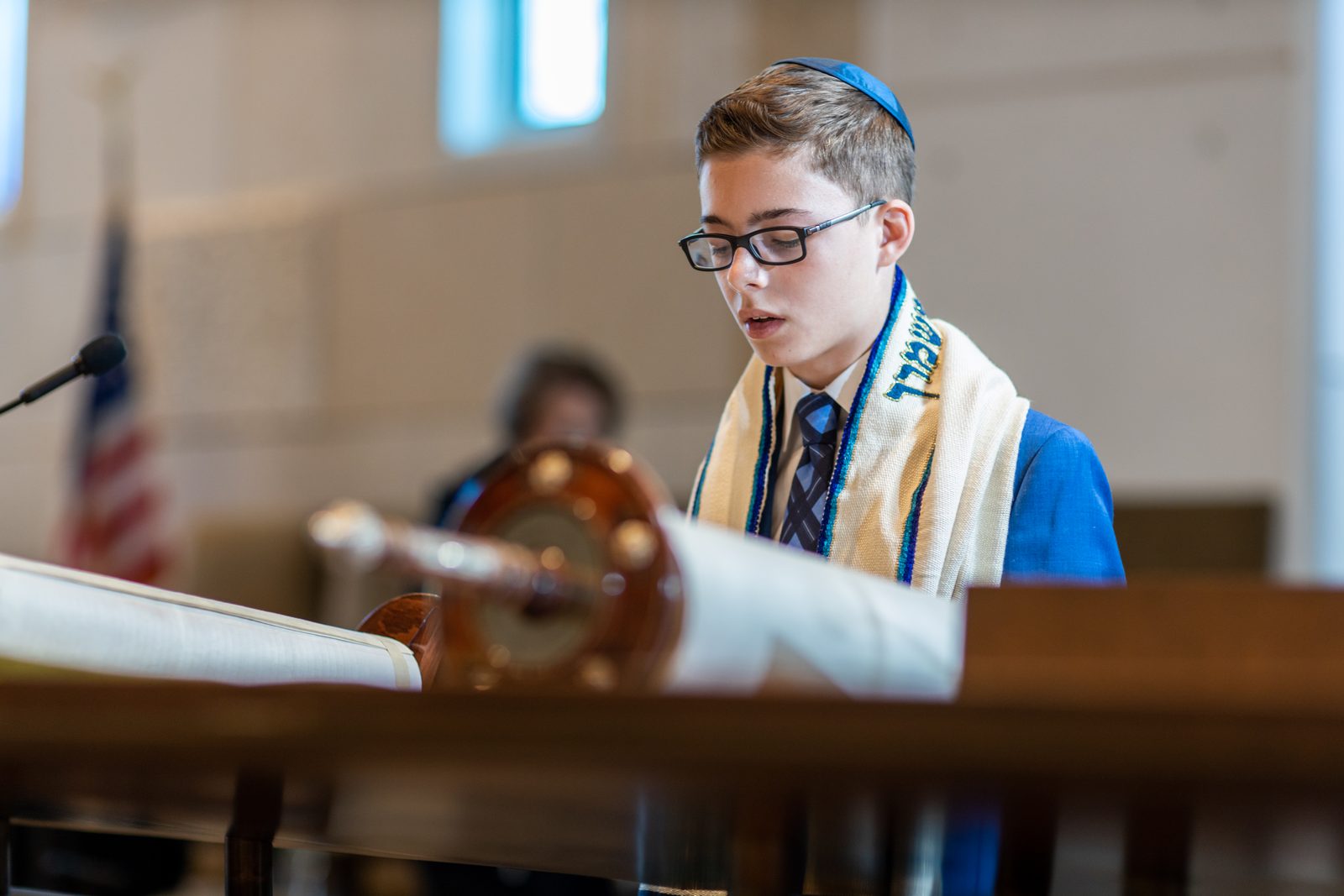 Bar mitzvah boy in tallit and kippah reading from the Torah