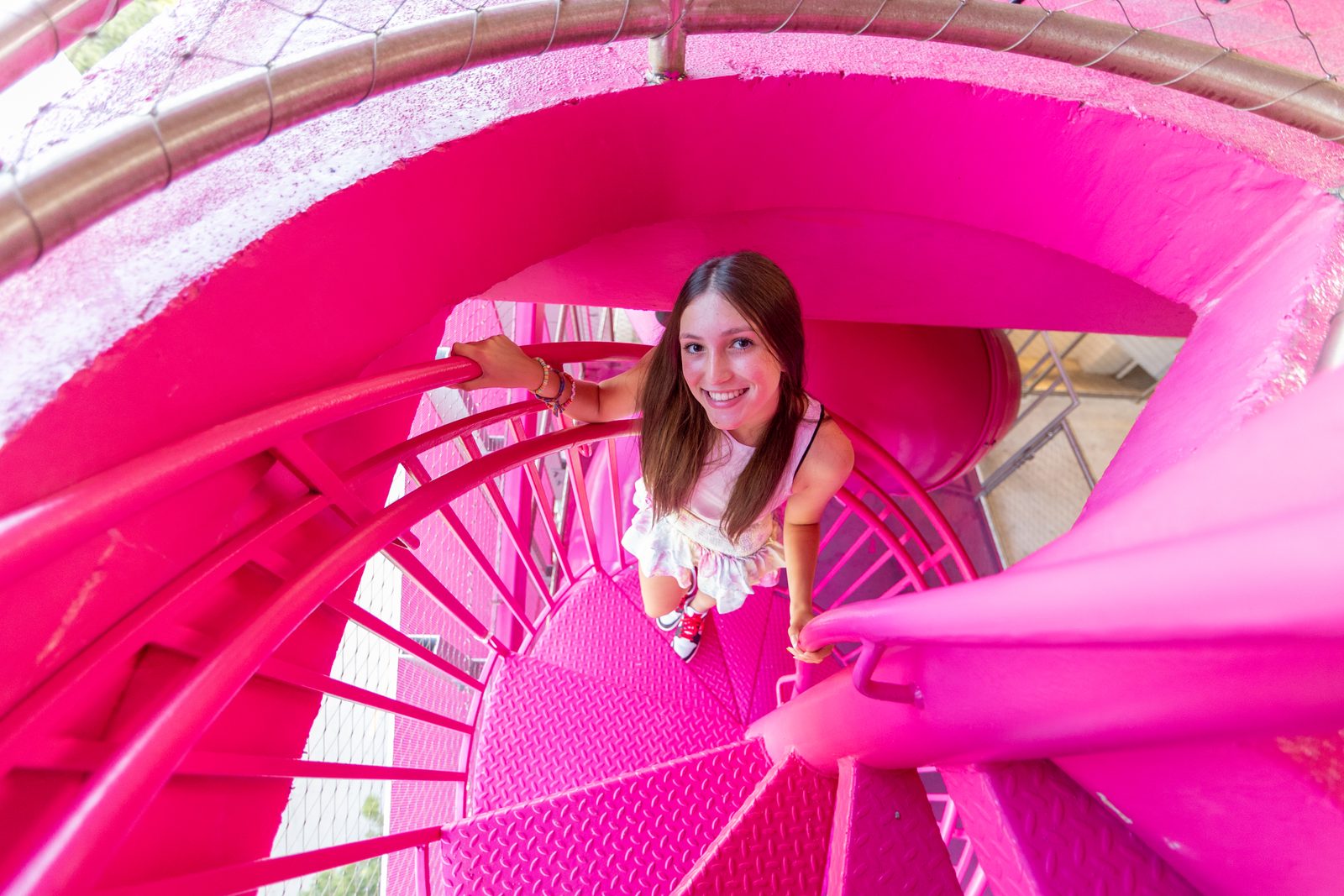 Bat mitzvah girl on a bright pink spiral staircase
