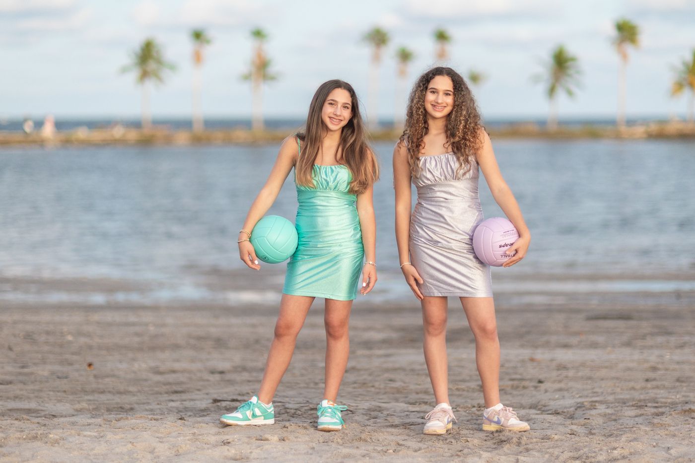 Two girls holding basketballs on a waterfront dock