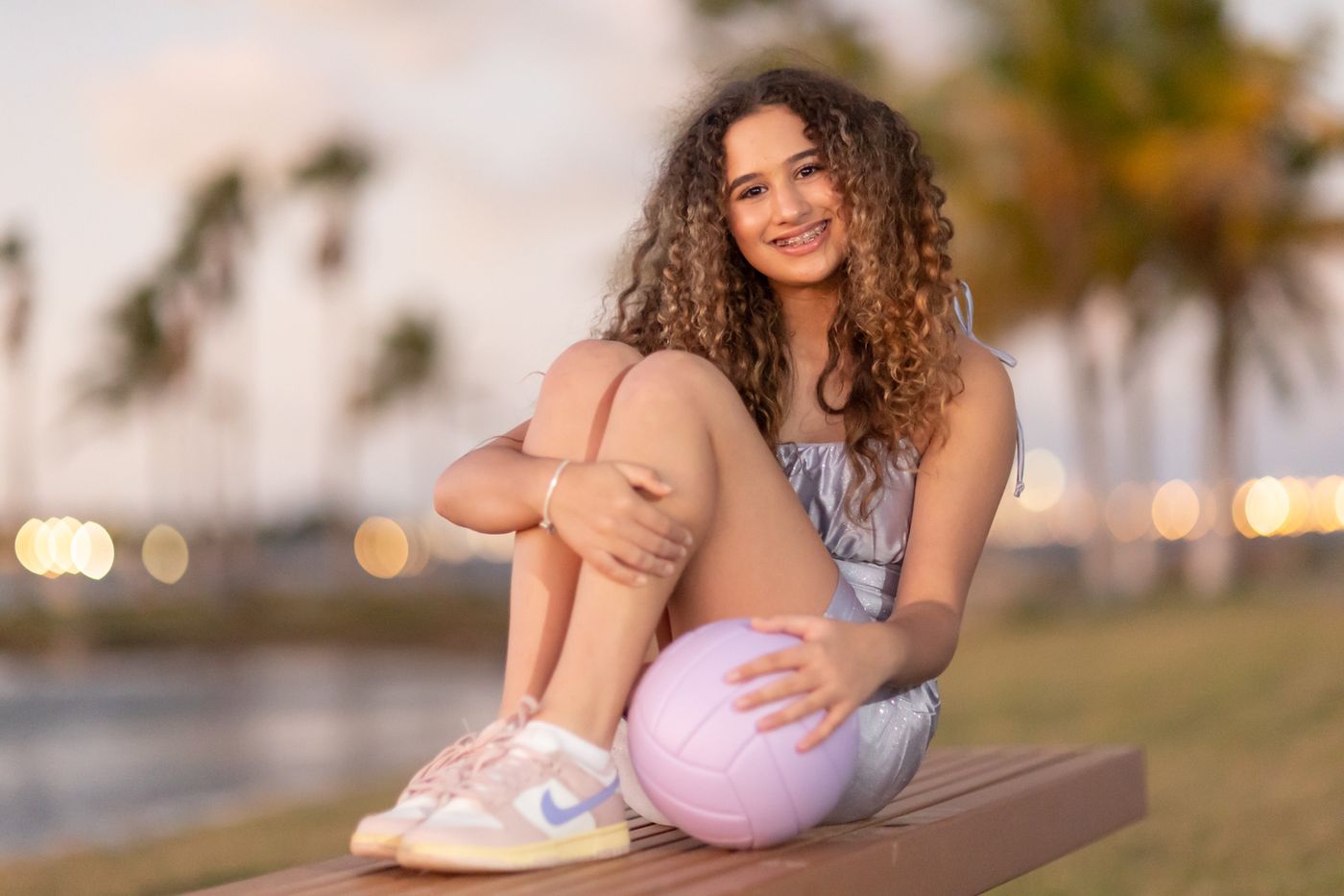 Girl sitting on a waterfront dock at sunset