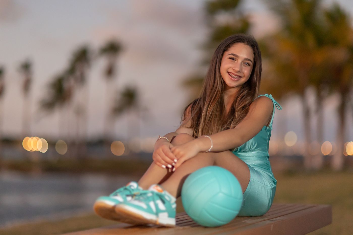 Girl sitting on a dock under a pastel sunset sky