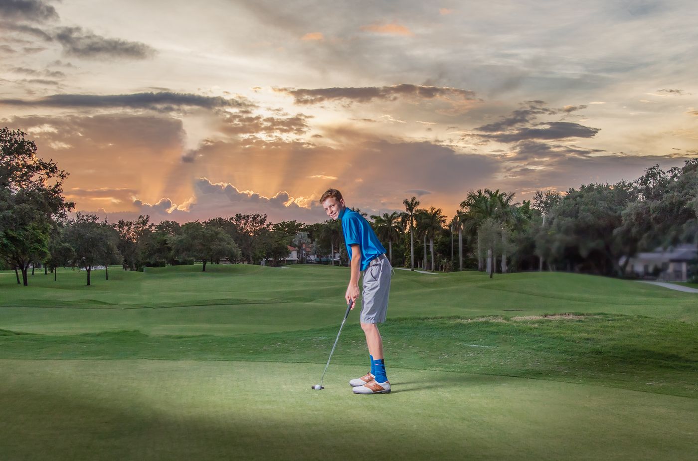 Boy golfing on a course at sunset