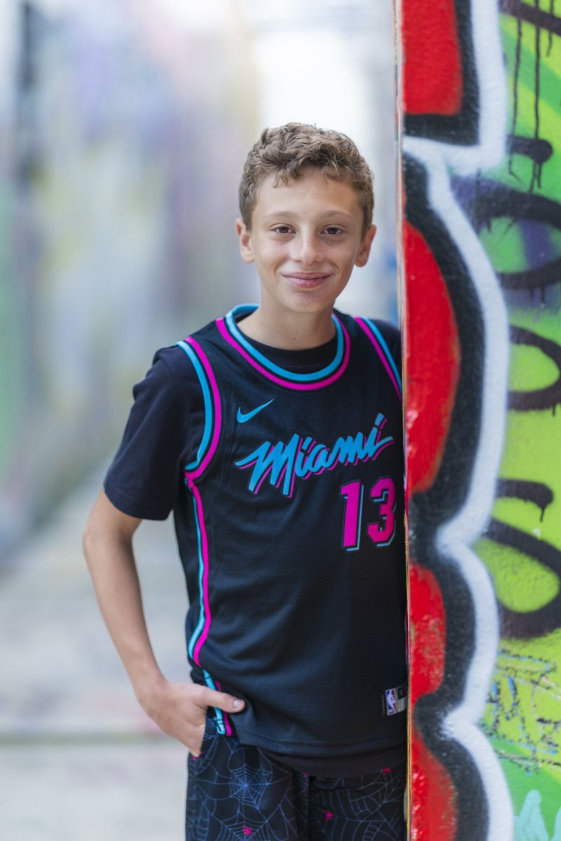 Boy in a basketball jersey against a graffiti wall