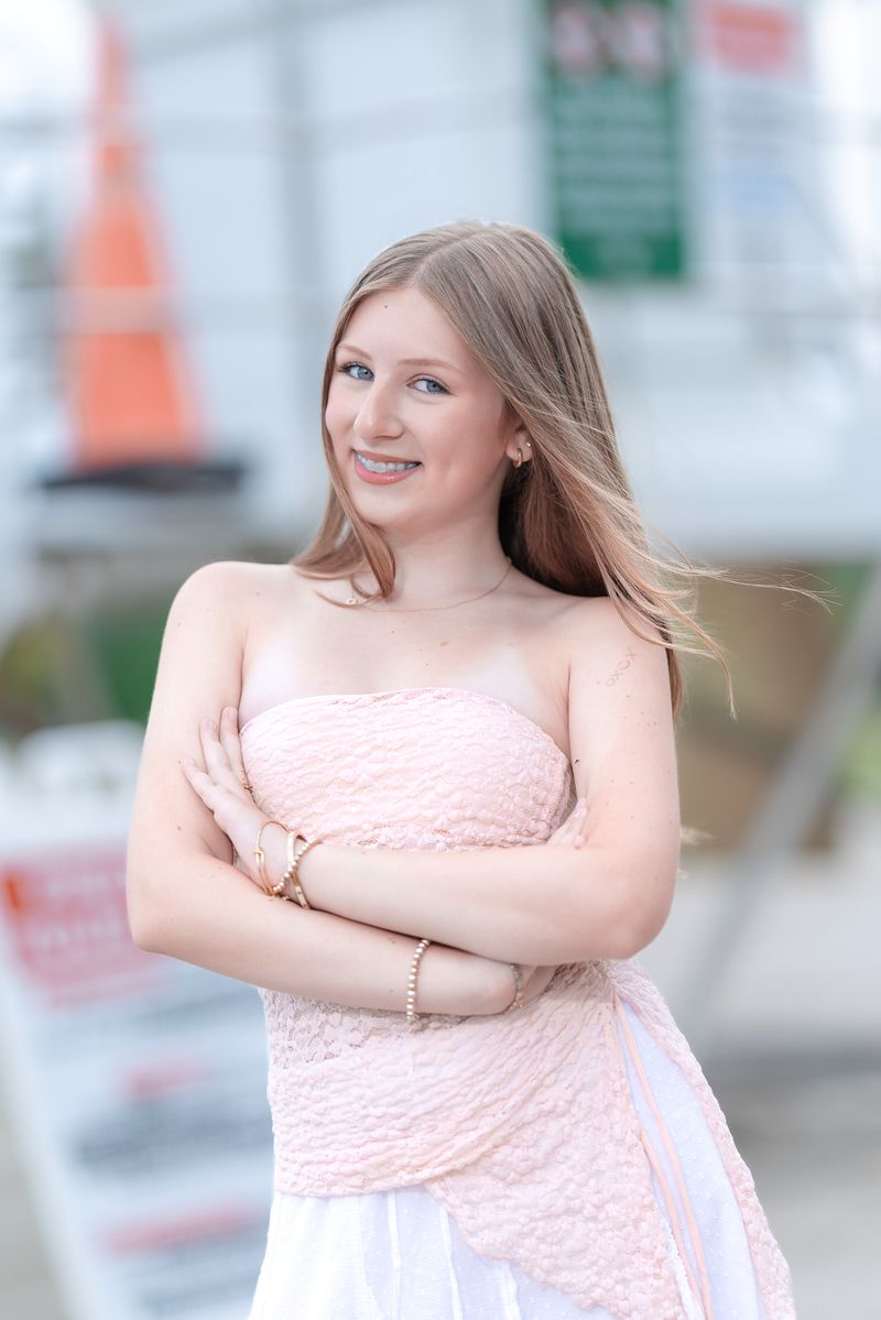 Girl in a pink dress by the water under a cloudy sky