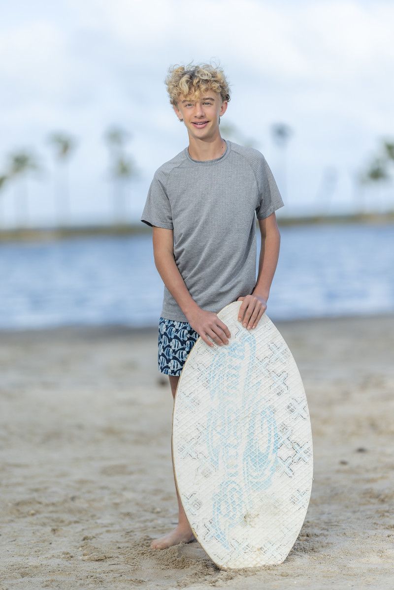 Boy holding a surfboard on the beach