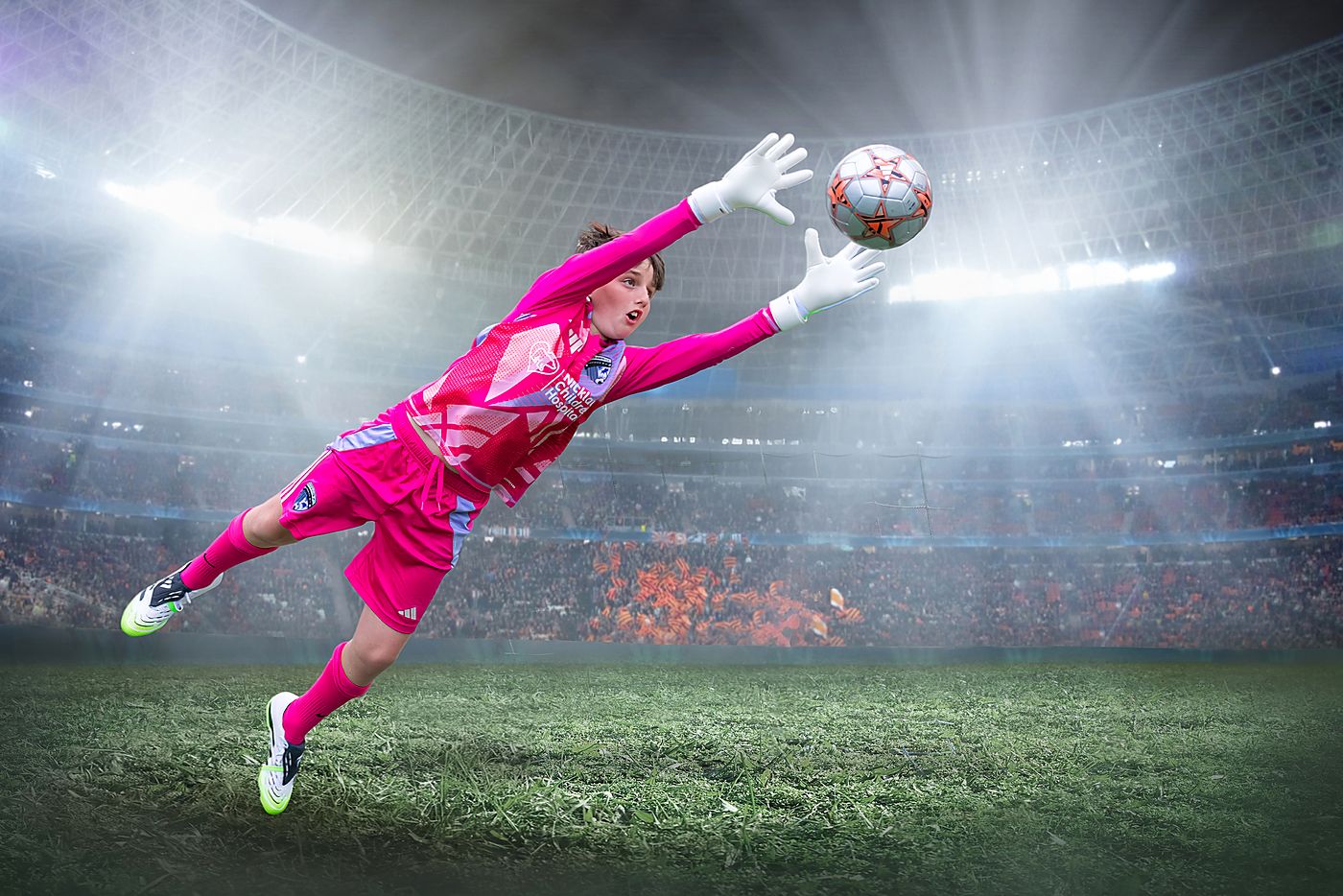 Young goalkeeper in a pink kit diving to make a save
