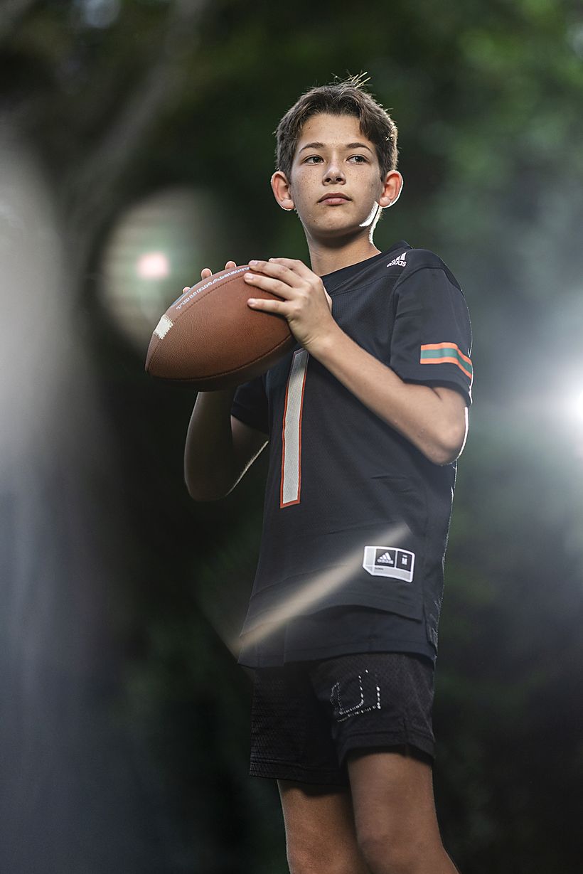 Boy in football pads and helmet holding a football