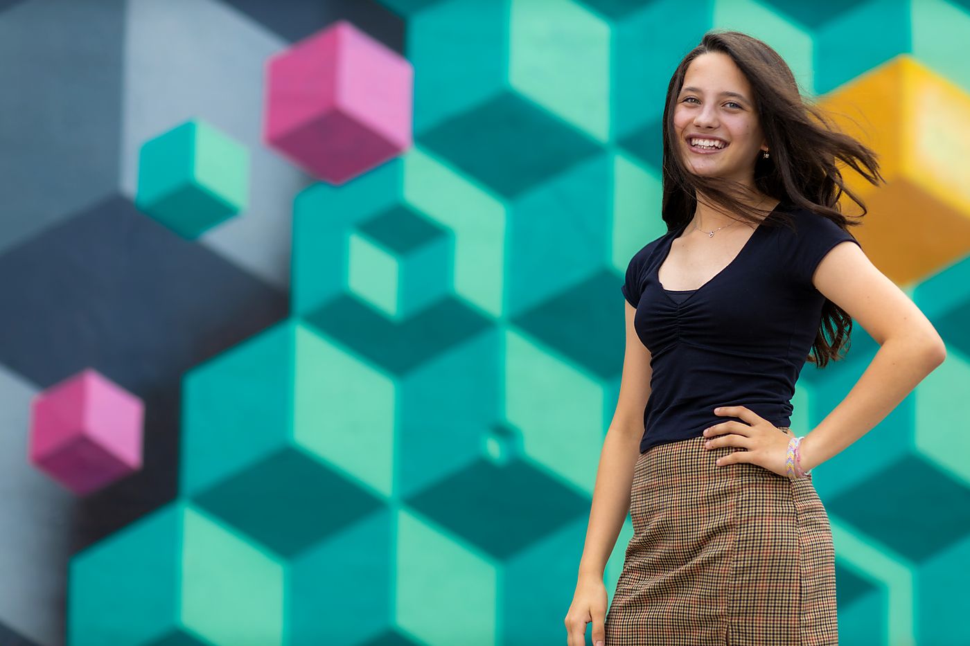 Girl in front of a bold geometric mural in teal, pink and orange