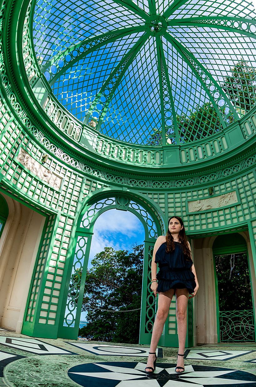 Girl standing inside a domed green ironwork pavilion