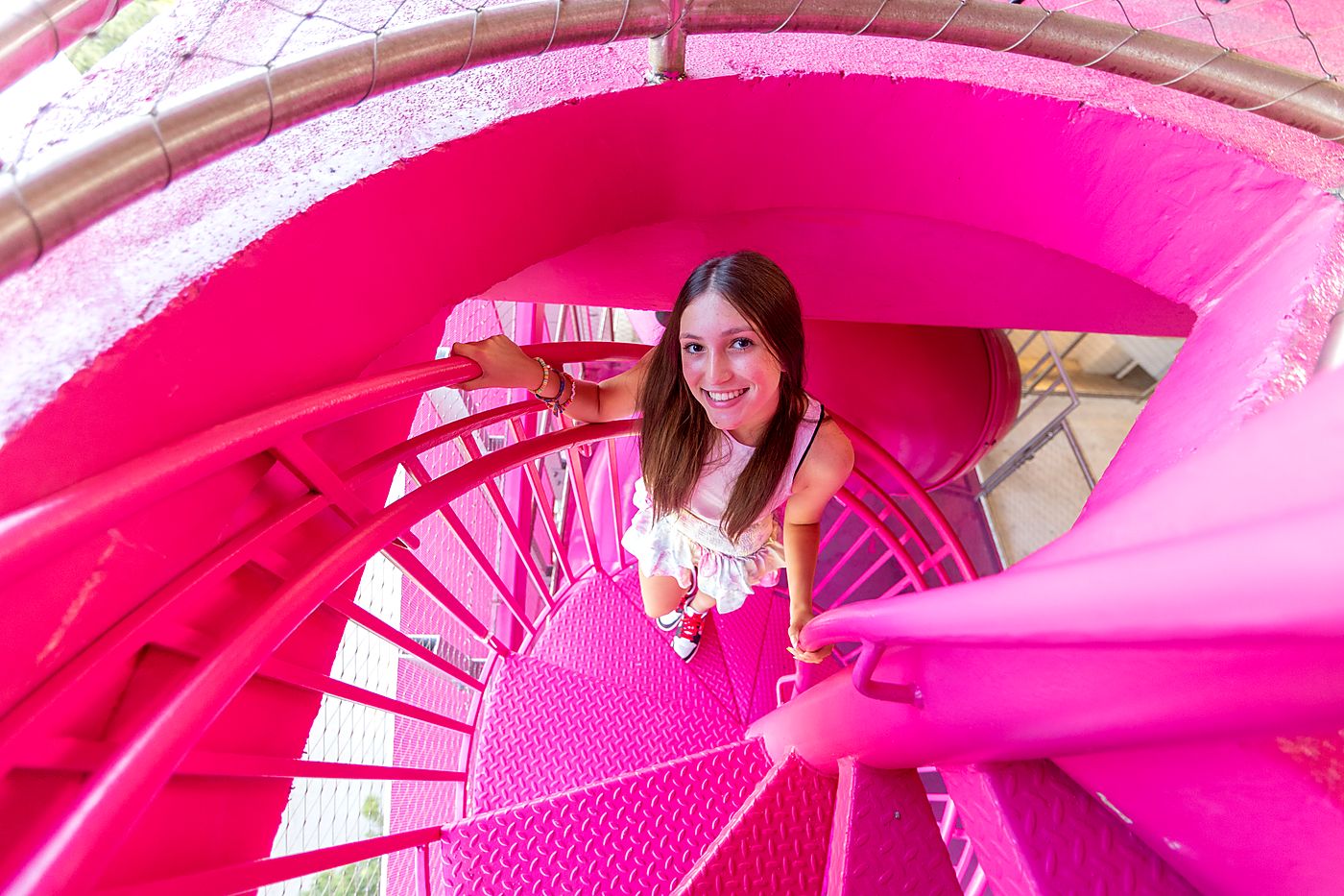 Girl on a bright pink spiral staircase