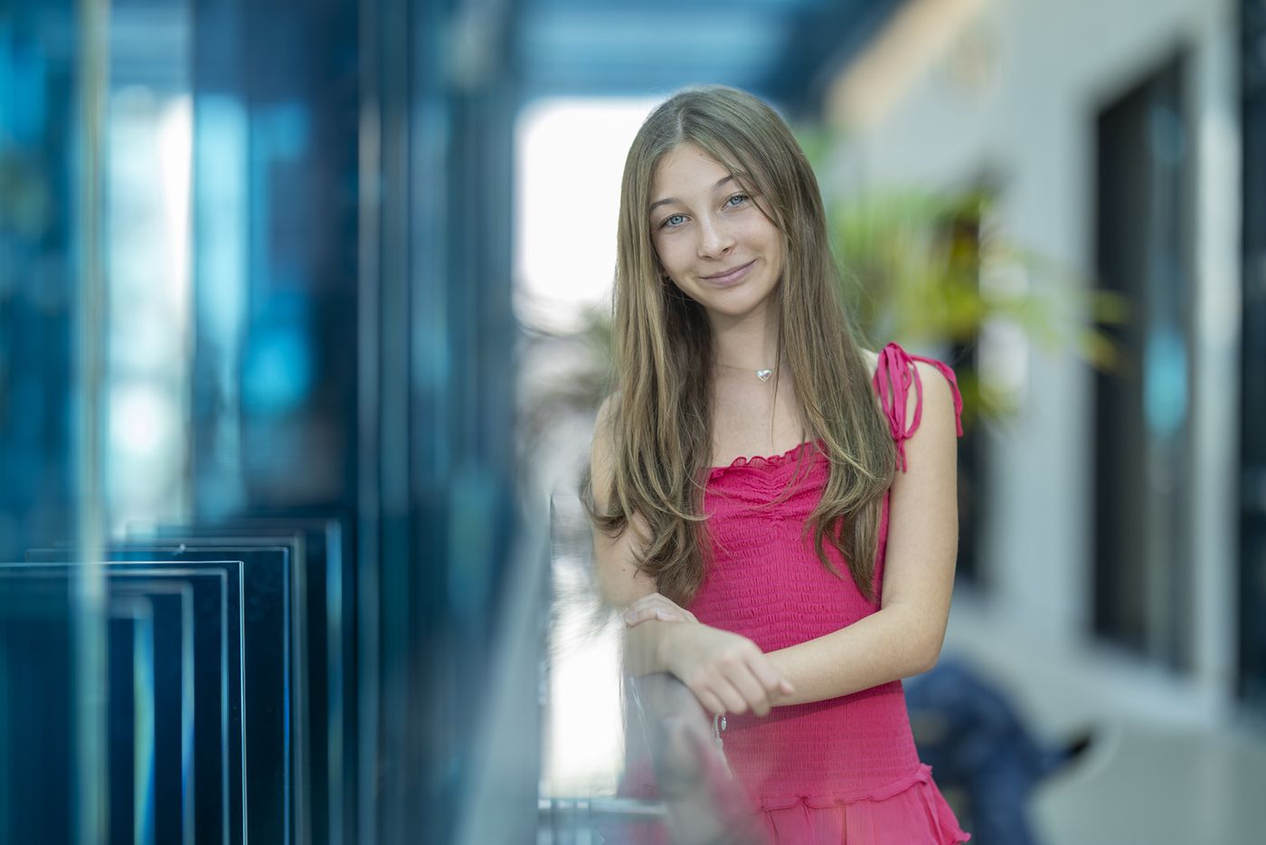 Girl in a pink dress in a modern glass hallway